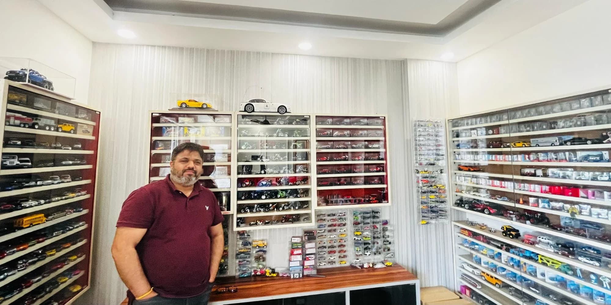 Rishi Kapoor, founder of 1isto64.com, in front of glass cabinets filled with diecast model cars